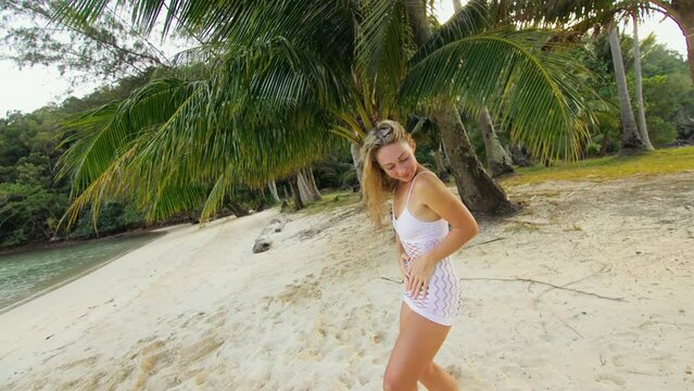 The chic girl dances an burning erotic dance in white dress in grid. The woman is having fun on an island vacation. Booty breast dancing twerk booty shake. Livestyle handheld shooting.