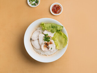 singapore food Sliced Fish Bee Hoon in a bowl with soup, chili sauce and spring onion top view on wooden table