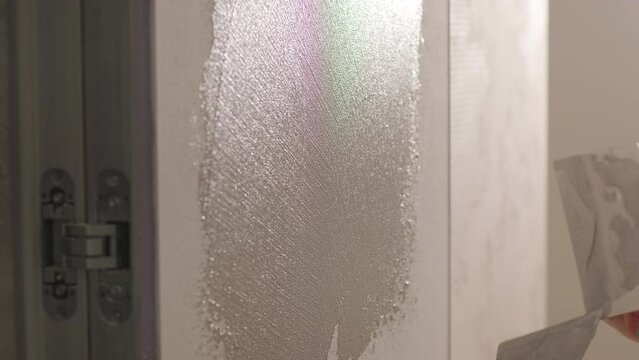 Worker applies decorative plaster with a thin spatula. Giving a unique texture t