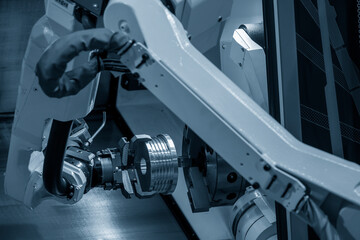 Fototapeta premium The automatic robotic arm gripping the metal parts from CNC lathe machine.