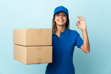 Young delivery woman isolated on blue background showing ok sign with fingers