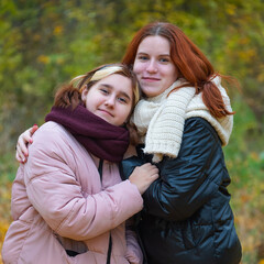 two red-haired smiling girls against the background of autumn nature, the concept of human emotions