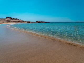 smooth waves of a turquoise sea gently touch the sandy Diakofti beach, Karpathos island, Greece.