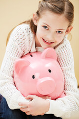 I always save my pocket money. Cropped portrait of a cute little girl smiling while holding a piggybank.