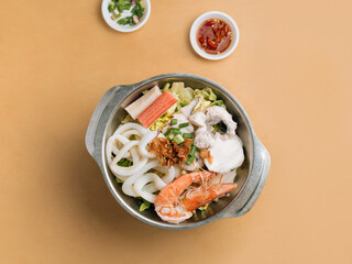 Seafood Xiao Wan in a bowl with soup, chili sauce and spring onion top view on wooden table
