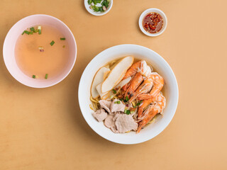 Asian food Spicy Prawn Noodle in a bowl with soup, chili sauce and spring onion top view on wooden table