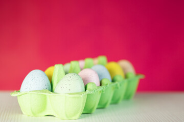Easter eggs in a box on pink background, space for text