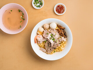 Black Soya Sauce Noodle in a bowl with soup, chili sauce and spring onion top view on wooden table