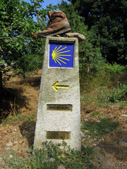 Calzado roto de un peregrino durante el camino de Santiago, colocado sobre un punto kilom&eacute;trico