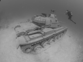scuba diver exploring tank wreck underwater
