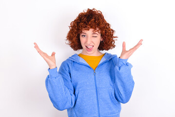 Crazy outraged young redhead girl wearing blue jacket over white background screams loudly and gestures angrily yells furiously. Negative human emotions feelings concept