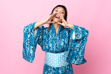 Young woman wearing kimono over isolated blue background shouting and announcing something