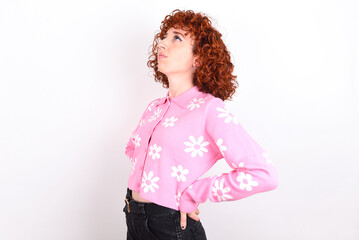 young redhead girl wearing pink floral t-shirt over white background  got back pain