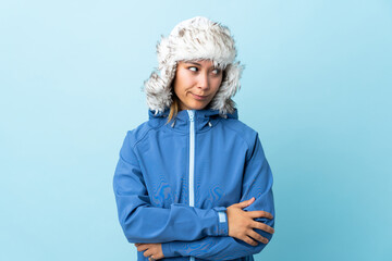 Young Uruguayan girl with winter hat isolated on blue background thinking an idea