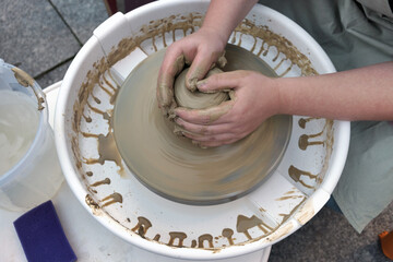 Close up hands working on pottery wheel and making a clay pot, selective focus