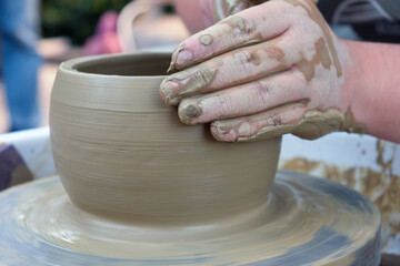 Close up hands working on pottery wheel and making a clay pot, selective focus