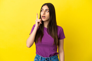 Young caucasian woman isolated on yellow background thinking an idea pointing the finger up