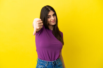 Young caucasian woman isolated on yellow background showing thumb down with negative expression