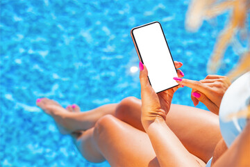 Woman using mobile phone by the pool, empty white screen mockup