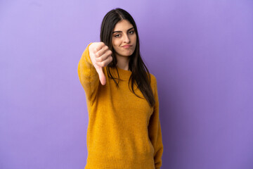 Young caucasian woman isolated on purple background showing thumb down with negative expression