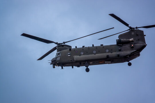 close up of an RAF Chinook tandem-rotor CH-47 helicopter flying fast and low in a cloudy blue grey sky on a military battle exercise, Wilts UK