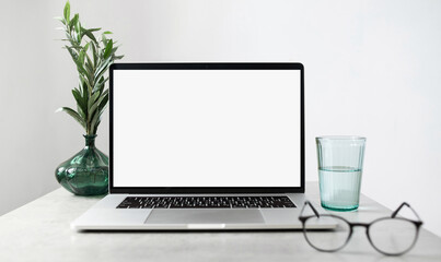 Fototapeta premium Laptop computer with empty blank mockup screen over white modern living room design. Home office, workplace, working or studying from home, distance learning, business concept
