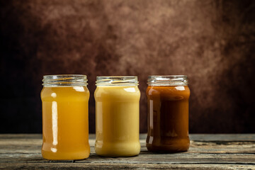 Collection of jars of different types of honey, light, dark and cream, Composition with three jars of honey, closeup