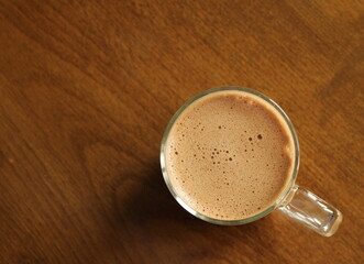 Cup of milk coffee on wooden table, top view, hot drink
