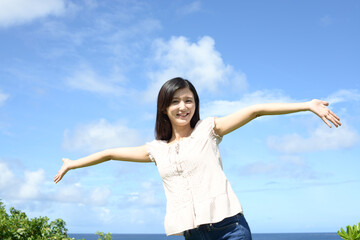 青空をバックに手を広げる女性