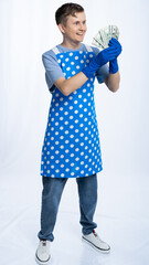 a man in a blue apron, rubber gloves, an orange t-shirt, jeans and white sneakers holds money,...