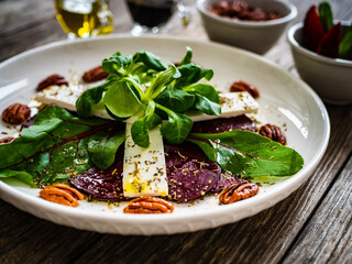 Beetroot carpaccio with goat cheese and pecan nuts  on wooden background

