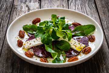 Beetroot carpaccio with goat cheese and pecan nuts  on wooden background
