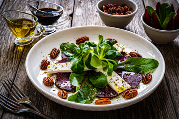 Beetroot carpaccio with goat cheese and pecan nuts  on wooden background
