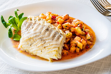 Fish dish - fried cod fillet with fresh fruit salsa on white table
