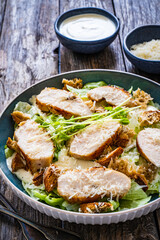 Caesar salad - fried chicken breast and vegetables on wooden table