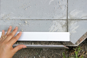 Above view of a hand of a person working out how to do the edge of a freshly tiled ceramic surface...