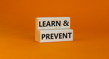 Learn and prevent symbol. Concept words Learn and prevent on wooden blocks on a beautiful orange table orange background. Business learning and learn and prevent concept, copy space.