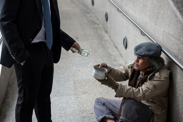 Businessman give 2 dollar bills to beggar in city