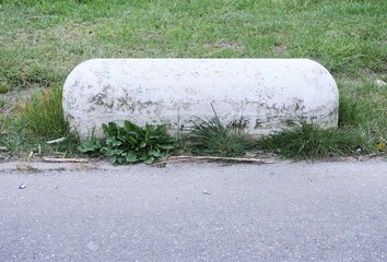 Semicircular, oblong boundary stone for a road or path, high enough to prevent vehicles from driving over the shoulder.