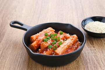 Tteokbokki or Topokki , stir fried rice cake stick, popular Korean street food with spicy gochujang sauce and sesame seed. 
