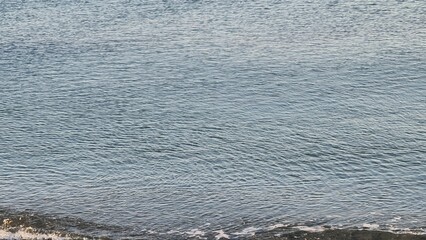 Obraz premium Savona, Italy - February 12, 2022: Panorama of the sea sunset, light above the water, ocean sunrise. Some little waves in winter days.