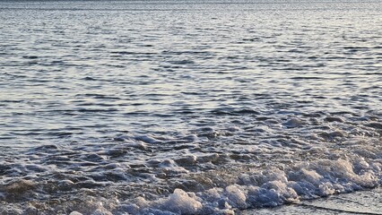 Savona, Italy - February 12, 2022: Panorama of the sea sunset, light above the water, ocean sunrise. Some little waves in winter days.