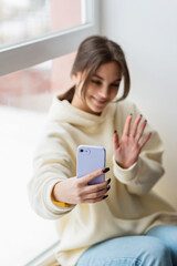 Happy female blogger taking selfie portrait on smartphone camera for social media posting, cheerful teenage girl talking on video call with family or friends via mobile phone.Soft selective focus.