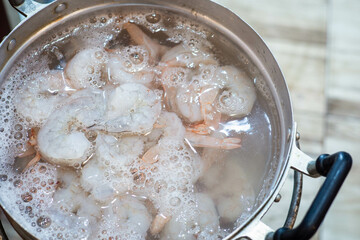 Raw shrimp in a pan of boiling water.