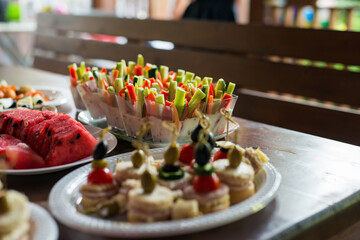 The buffet at the reception. Assortment of canapes on wooden board. Banquet service. Catering, snacks with different types of cheese and meat. Party Concept.