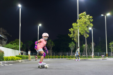asian child or kid girl playing surf skate or skateboard in skating rink or sport public park at...