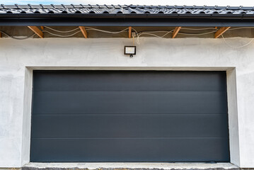 Closed anthracite garage door with a visible lamp for the motion sensor, view from the outside.