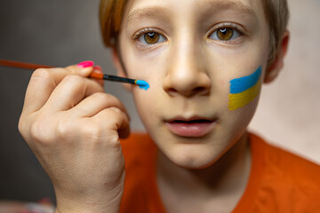 a child against war, a boy with a painted flag of Ukraine on his cheeks