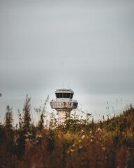 Air control tower at the airport with clouds and a field on the foreground