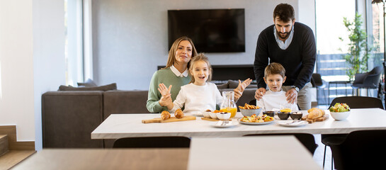 Young happy family talking while having breakfast at dining table